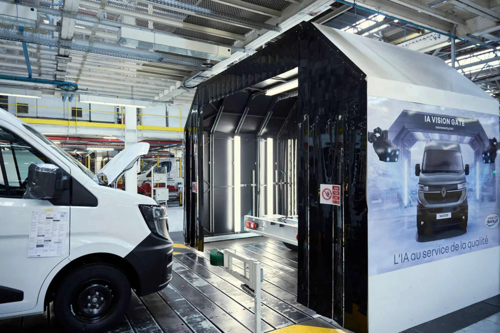 Una furgoneta Renault Master blanca en una estación de inspección de vehículos situada dentro de la luminosa fábrica de Batilly, donde se exhiben equipos industriales y se aplican altos estándares para los clientes profesionales.