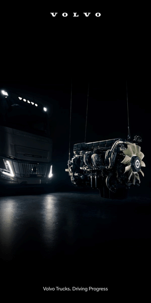 Un camión Volvo con el motor suspendido aparece en un entorno oscuro, en el banner A, posición 01. El texto dice: «Volvo Trucks. Driving Progress». Ideal para pantallas de ordenador.