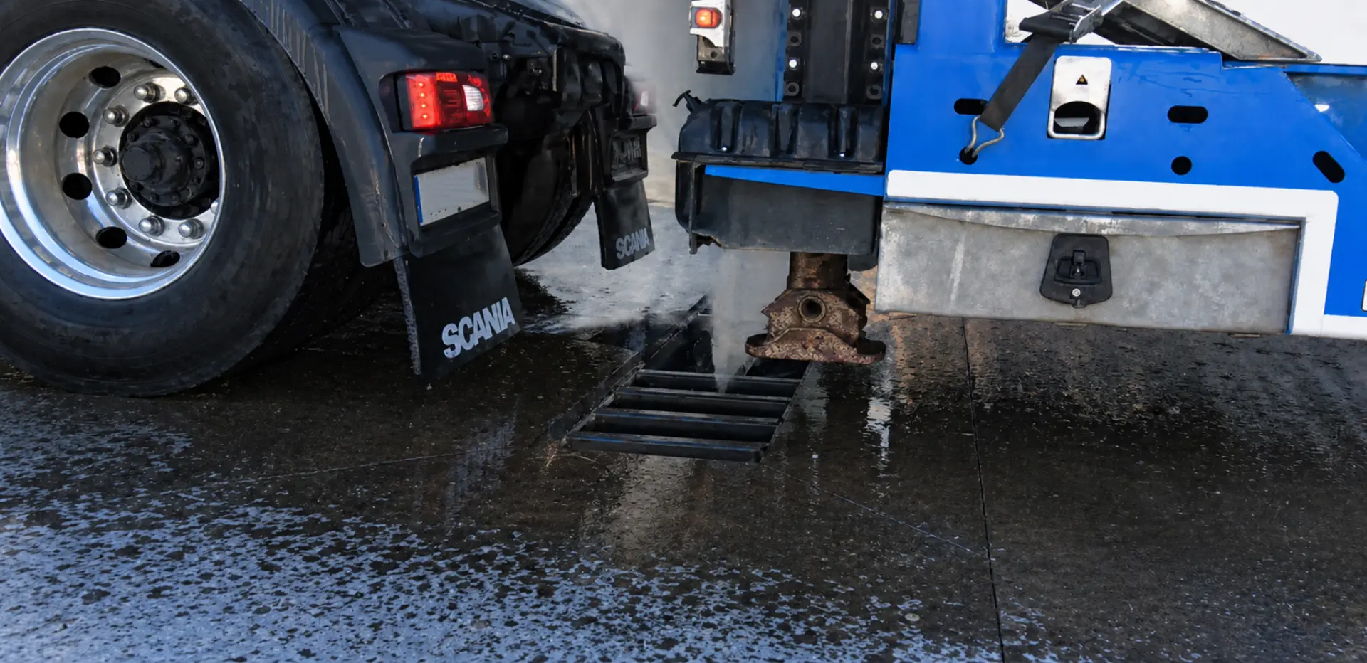 Un camión de Vision Wash está vertiendo líquido sobre el asfalto mojado cerca de una alcantarilla, salpicando agua por todas partes, lo que demuestra cómo la ingeniería propia puede mejorar la rentabilidad de las flotas mediante operaciones eficientes y respetuosas con el medio ambiente.