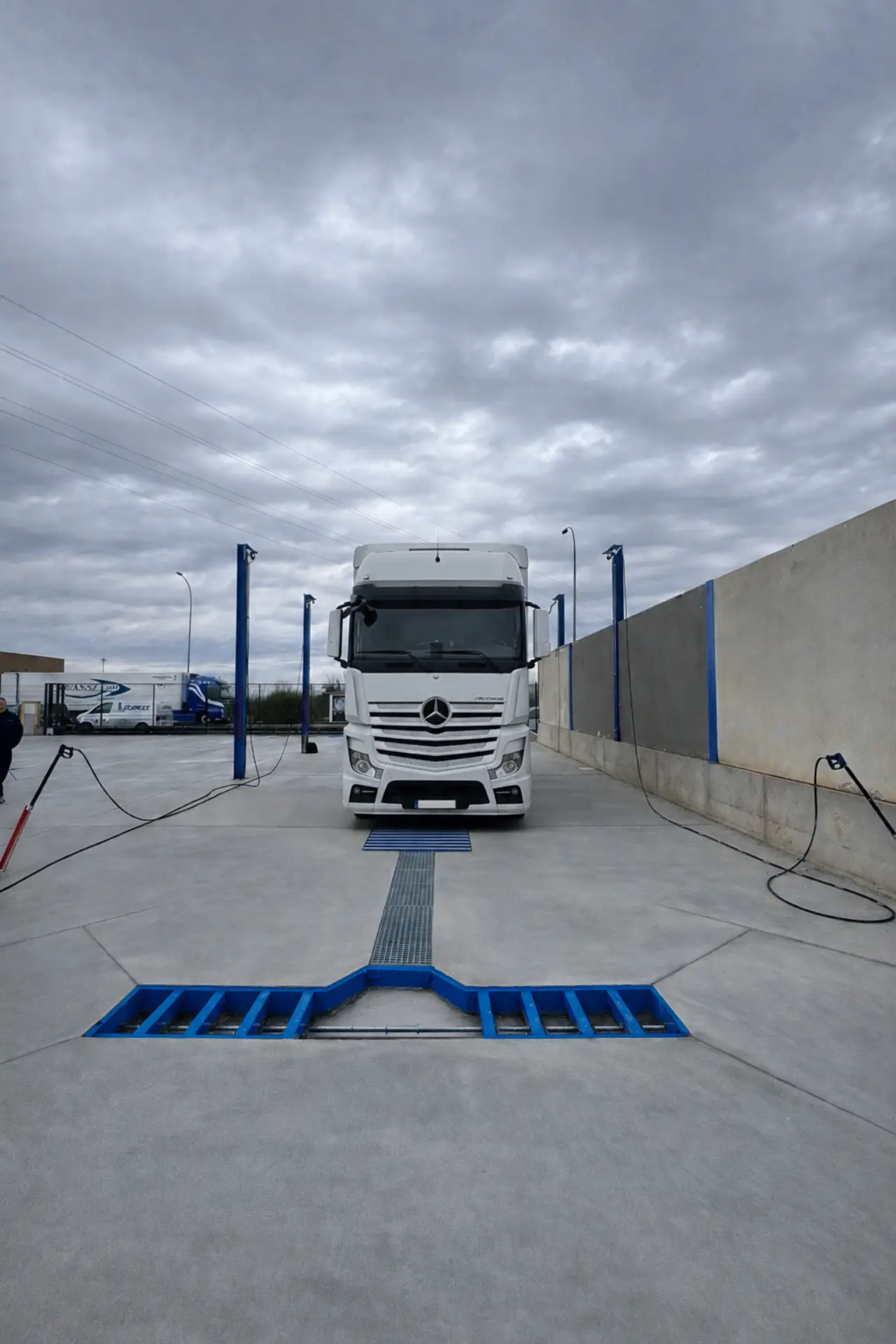 Una furgoneta Mercedes-Benz blanca, fabricada con ingeniería propia, está aparcada en un terreno de hormigón bajo un cielo nublado, de cara a la cámara.