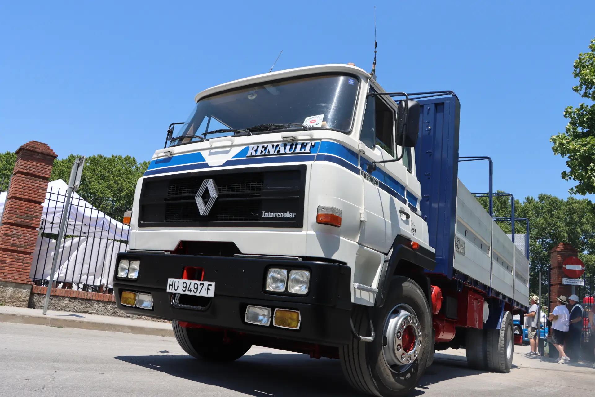 Una furgoneta Renault blanca aparcada en una calle a la luz del sol, con árboles y un edificio al fondo: un auténtico momento «cocotruckergirl» y quizá parte de una concentración en homenaje a Oti Cabadas.