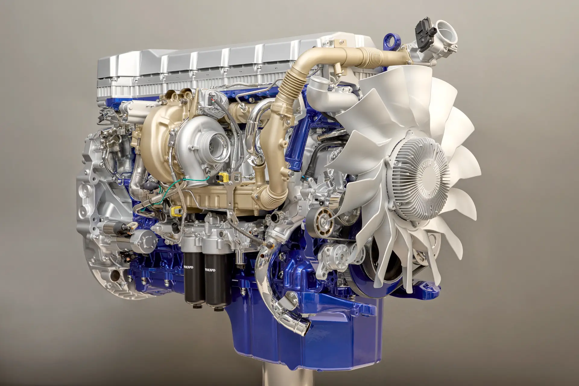 Motor diésel Volvo grande, de color azul y plateado, con un ventilador de refrigeración blanco, mangueras y diversos componentes mecánicos.