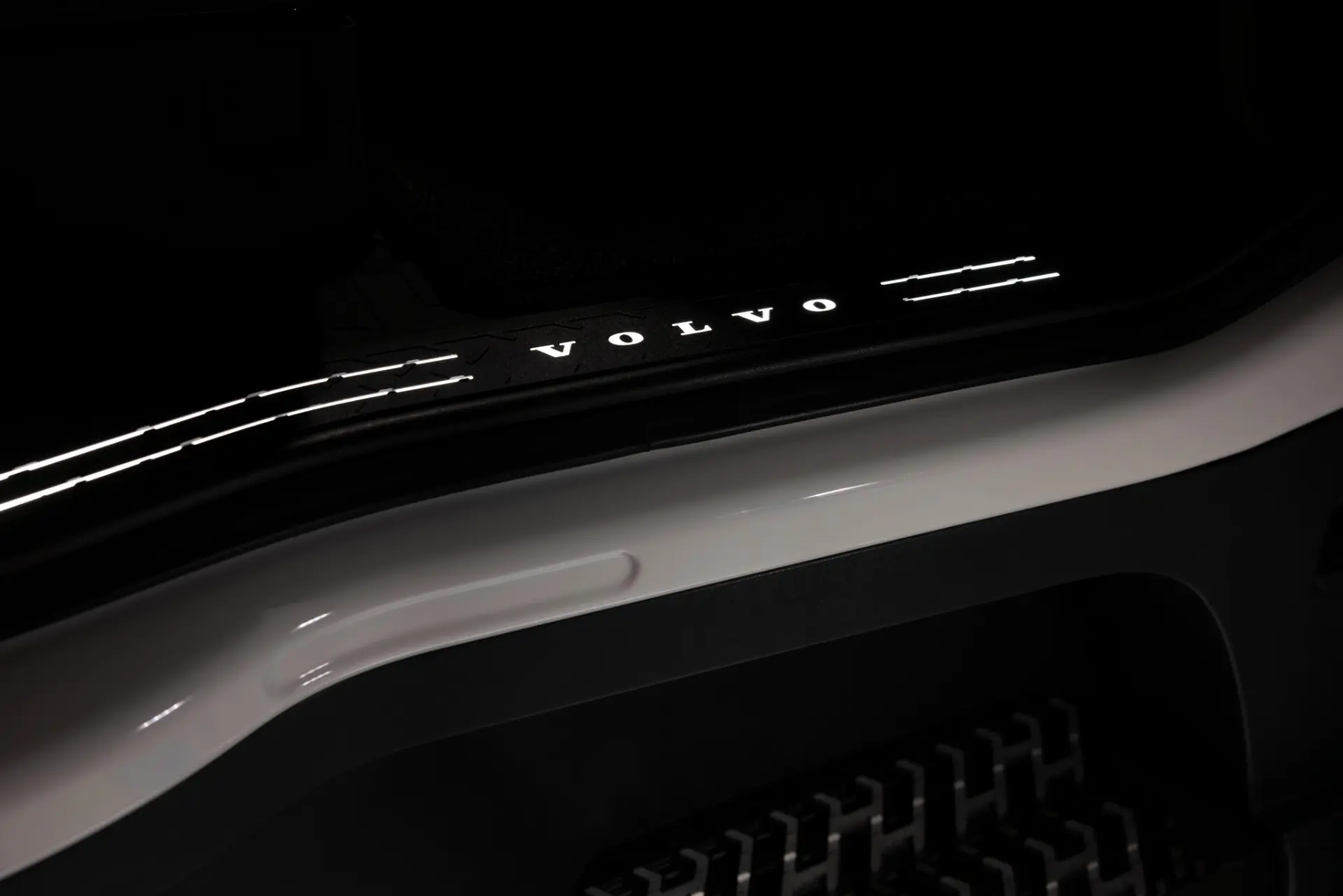 El logotipo «VOLVO» iluminado en el umbral de la puerta de un coche, con el interior negro y las molduras blancas a la vista: este detalle evoca la refinada artesanía que caracteriza al Volvo FH16 Aero edición especial.