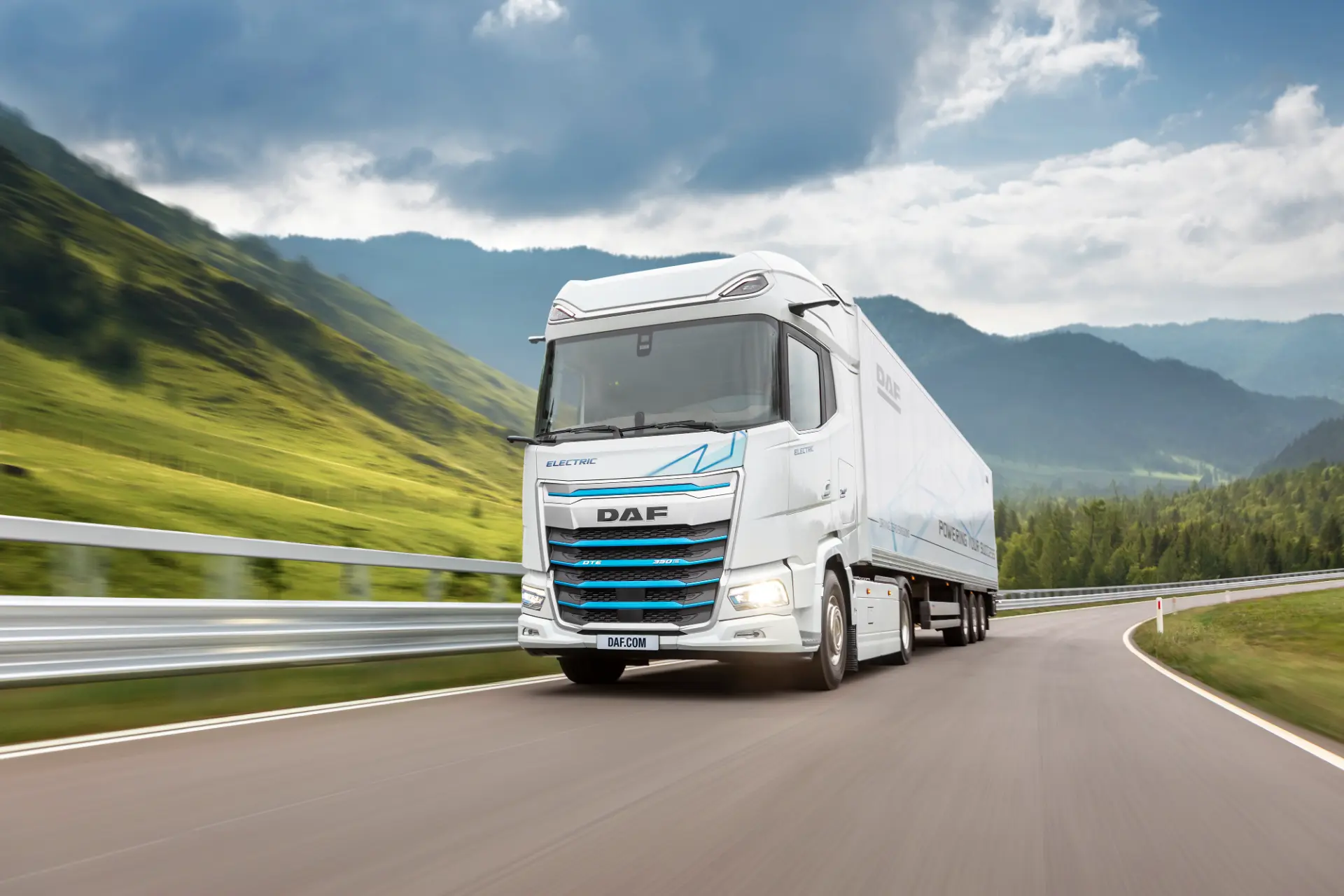 Un camión DAF XD Electric blanco circula por una autopista a través de un paisaje verde y montañoso bajo un cielo nublado, mostrando el futuro del transporte con cero emisiones de cara a la feria IAA Transportation 2026.