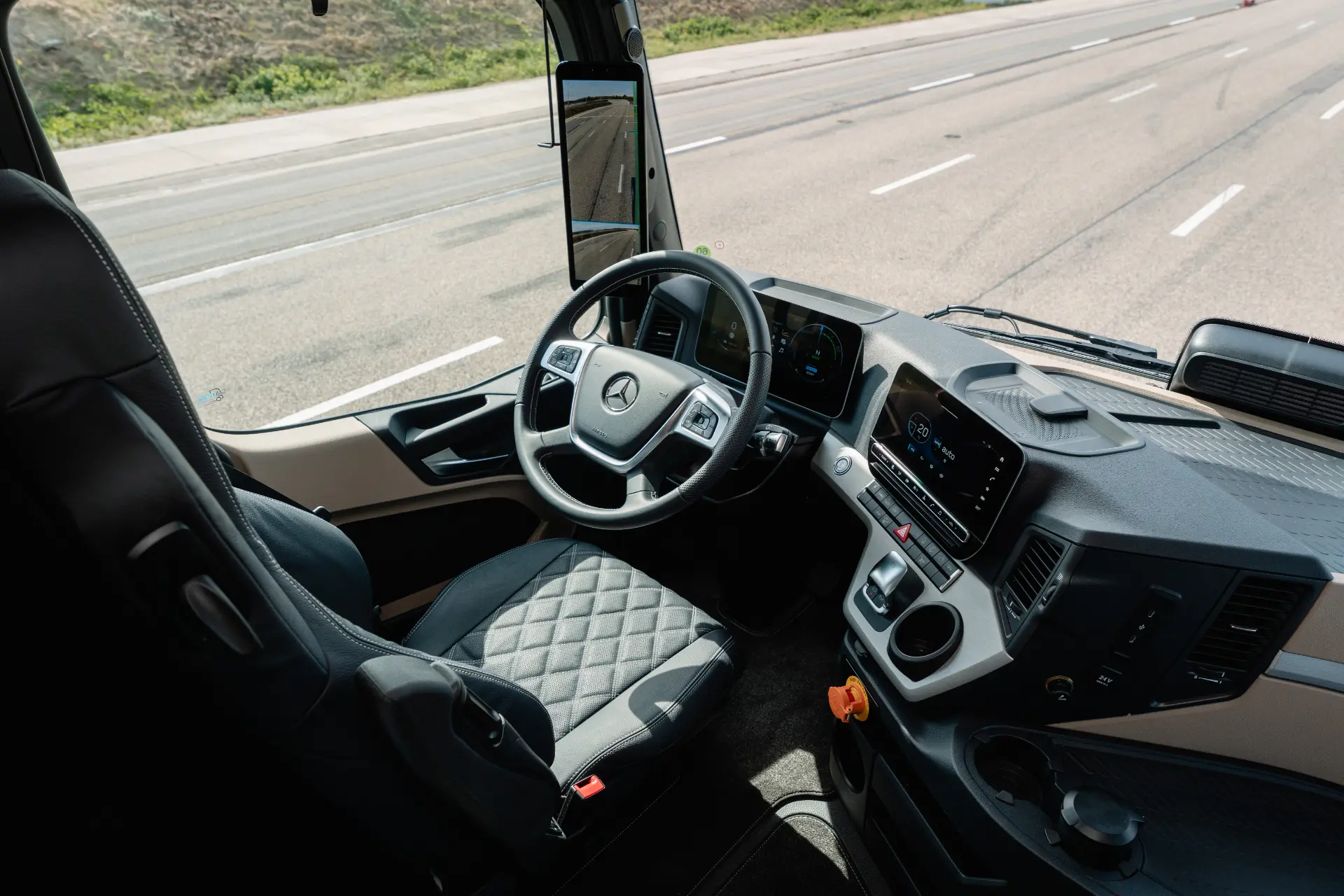 Interior de la cabina de un camión moderno de Mercedes-Benz, en el que se aprecian el asiento del conductor, el volante y el salpicadero, diseñados para reflejar la tecnología avanzada y el confort que ofrece el eActros Lowliner, que forma parte de la innovadora gama de camiones eléctricos de Mercedes-Benz, como el eActros 600.
