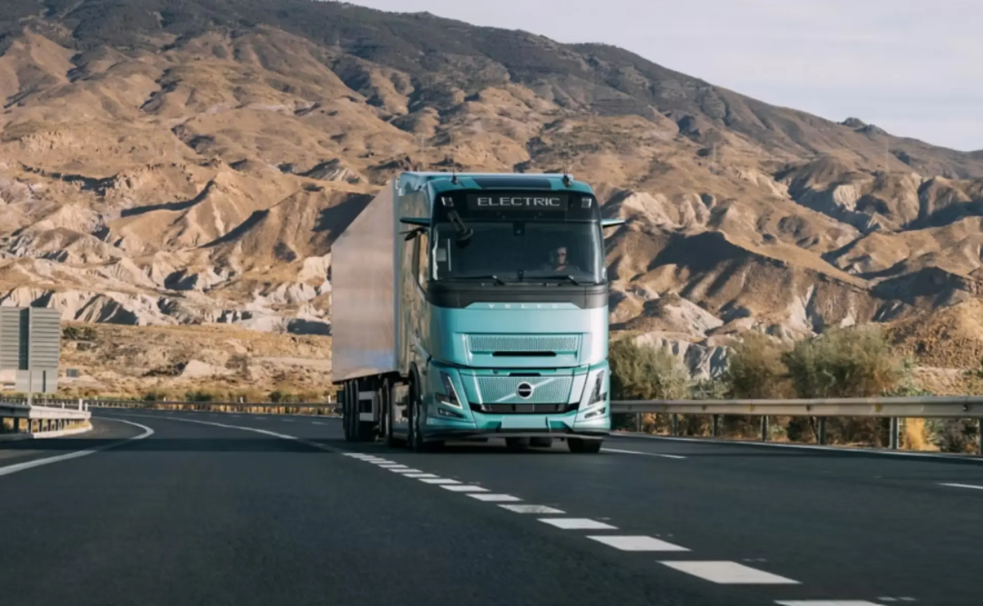 Un camión Volvo FH Aero Electric de color turquesa circula por una autopista con las montañas de fondo, mostrando el futuro de la tecnología de los camiones eléctricos de cara a la IAA 2026.