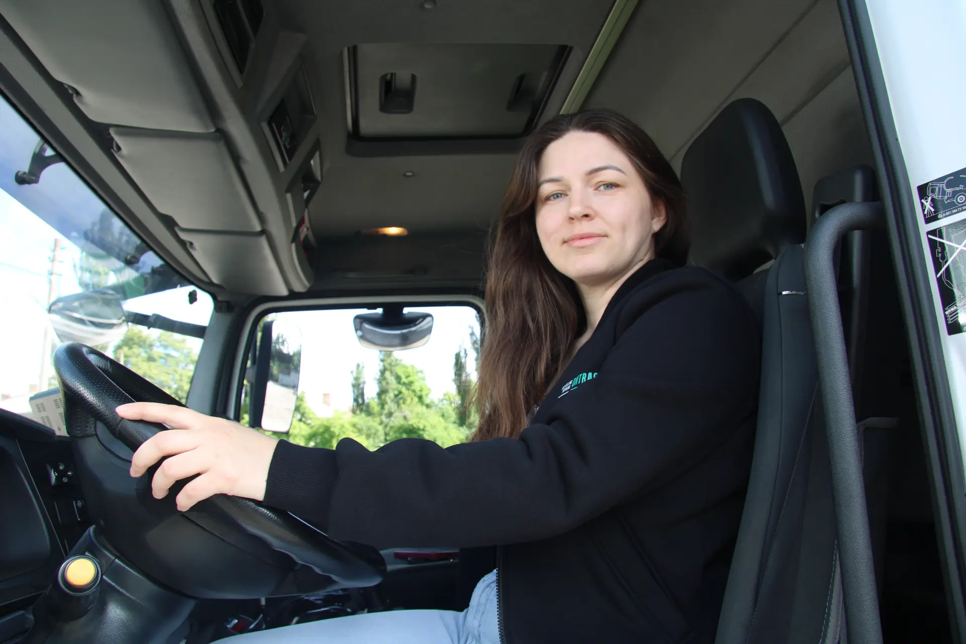 Un camionero ucraniano está sentado en el asiento del conductor, con las manos en el volante.