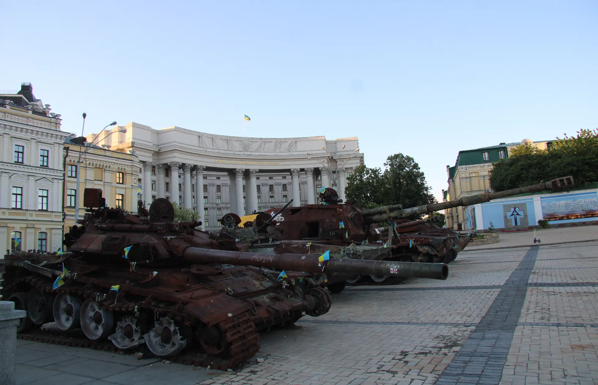 Tanques destruidos decorados con banderas ucranianas frente a un edificio gubernamental.
